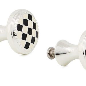 May include: Two silver-toned metal cabinet knobs featuring a circular face with a black and cream-colored checkered diamond pattern. Each knob has a beaded edge detail and a threaded metal screw extending from the back for installation purposes.