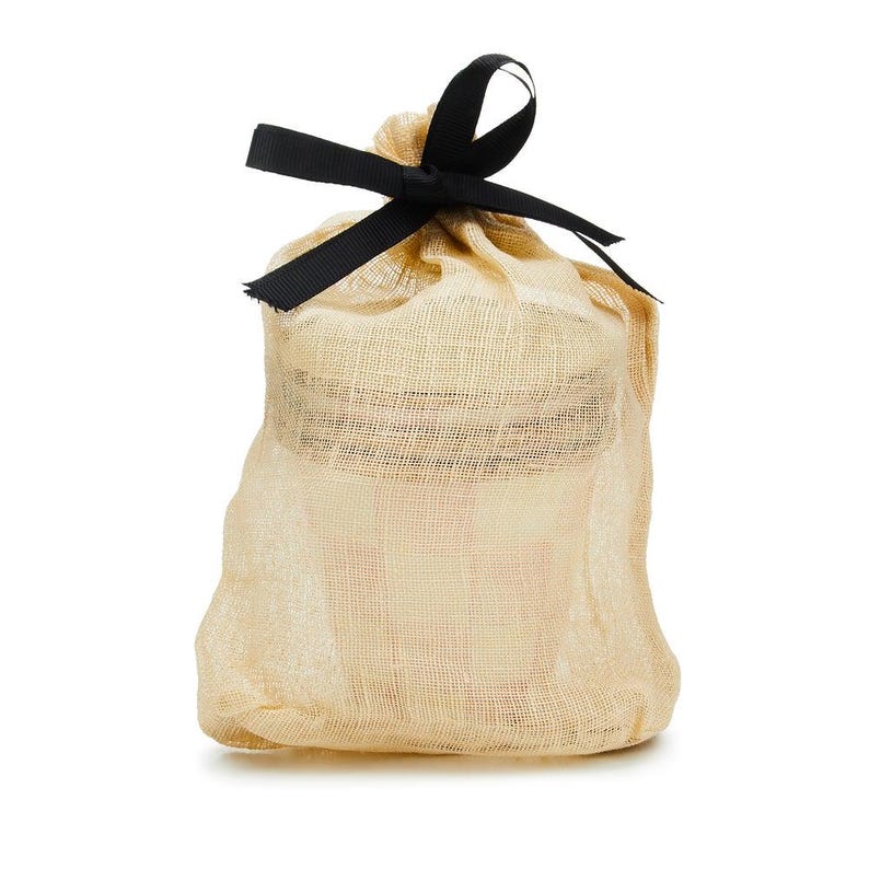 May include: A small, semi-sheer beige drawstring pouch made of a fine, woven fabric. The bag is cinched at the top with a black ribbon tied into a bow, securing the contents inside while allowing a glimpse of the item through the mesh material.