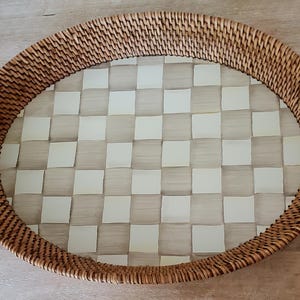 Puede incluir: Bandeja ovalada de rat&aacute;n tejido con un patr&oacute;n interior a cuadros. El borde de la bandeja est&aacute; hecho de rat&aacute;n tejido apretadamente, y el interior presenta una cuadr&iacute;cula de cuadrados claros y blanquecinos alternados. Esta bandeja decorativa es adecuada para servir o exhibir.