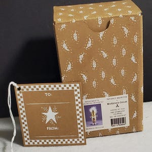 May include: A brown cardboard box and gift tag set with white leaf and dot patterns. The tag reads "TO:" and "FROM:" with a star design. The box has product information and a picture of an ornament.