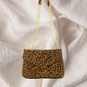 May include: A brown and black leopard print crossbody bag with a gold chain strap.