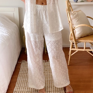 May include: White eyelet pants with a wide leg and a geometric pattern. The pants are made of a lightweight fabric and have a comfortable fit.