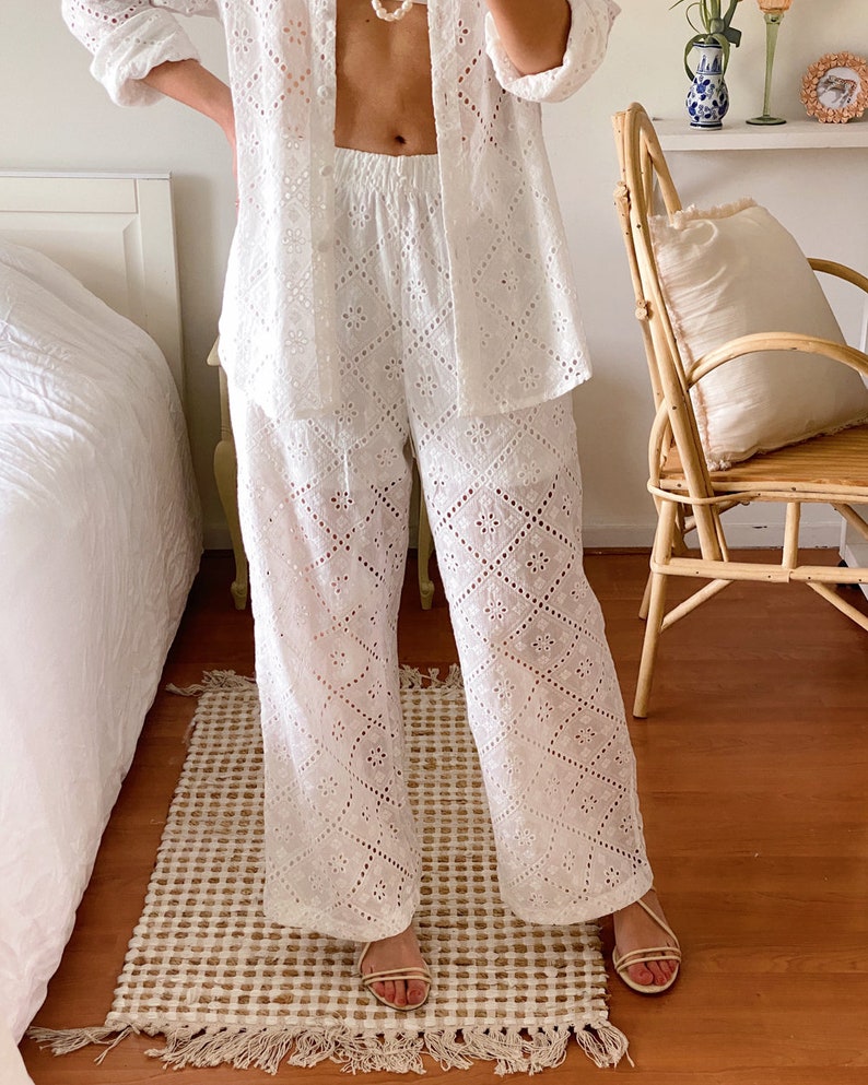 May include: White eyelet pants with a wide leg and a geometric pattern. The pants are made of a lightweight fabric and have a comfortable fit.