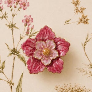 May include: A decorative cabinet knob shaped like a five-petaled flower with deep magenta outer petals, lighter pink inner petals, and a textured gold-toned centre. The edges of each petal are outlined in a thin, metallic gold-coloured trim.