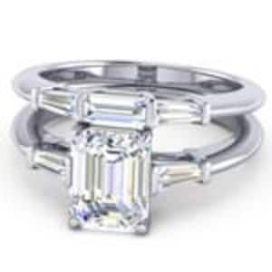 Puede incluir: Un anillo de compromiso de plata con una piedra central grande de corte esmeralda y dos piedras más pequeñas de corte baguette a cada lado.