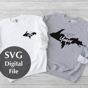 Puede incluir: Dos sudaderas con un contorno negro de la península superior de Michigan y el texto "I'd rather be a Yooper". Una sudadera es blanca y la otra es gris.