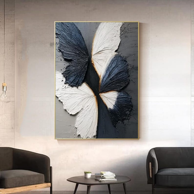 Pu&ograve; includere: Opera d'arte astratta a farfalla. L'opera presenta un design strutturato e tridimensionale di una farfalla con ali nei toni del bianco e blu navy. L'opera &egrave; incorniciata in una cornice dorata e posta su uno sfondo grigio.