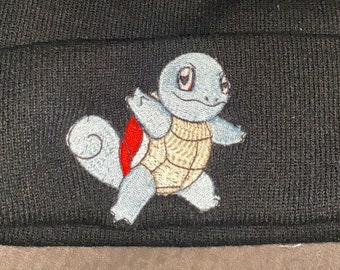 May include: Black beanie with an embroidered Squirtle design. The beanie is made of a soft, knitted fabric and features a fold-over cuff.