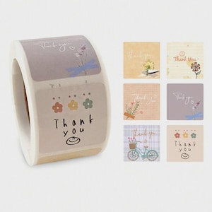 May include: A roll of decorative stickers with a "Thank You" theme. The stickers feature floral and bicycle designs, with the words "Thank You" in a handwritten font. The color palette includes pastel shades of pink, blue, and green.
