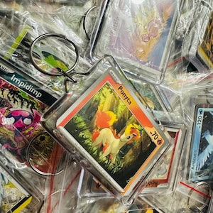 Pu&ograve; includere: Una collezione di carte da scambio Pok&eacute;mon in buste di plastica, con personaggi come Impidimp, Ponyta e Articuno. Le carte sono attaccate a portachiavi, il che le rende perfette per collezionisti o fan.