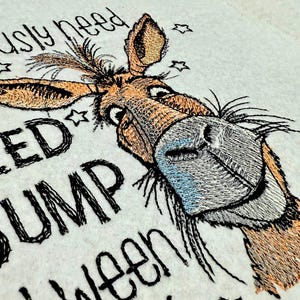 May include: Embroidered design of a donkey with the text "I seriously need a dump between", a humorous design for a t-shirt or tote bag.