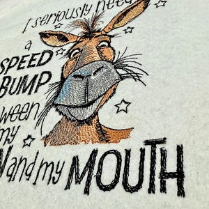 May include: Embroidered design of a donkey with the text "I seriously need a speed bump between my hand and my mouth".
