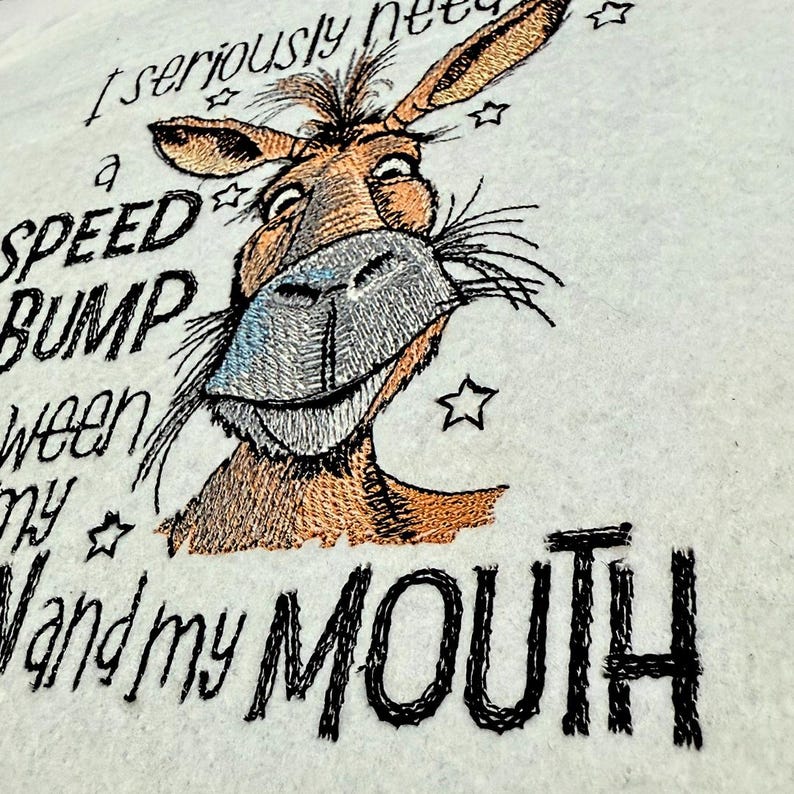 May include: Embroidered design of a donkey with the text "I seriously need a speed bump between my hand and my mouth".