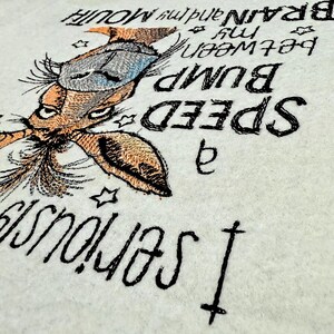 May include: Embroidered design on a white fabric featuring a cartoon animal with a long nose and large ears. The text reads "I seriously  a SPEED BUMP  between my BRAIN and my MOUTH".