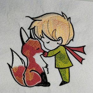 May include: Embroidered image of a young boy with blond hair and a green jacket kissing a red fox with a white tail. The boy is wearing a red scarf.