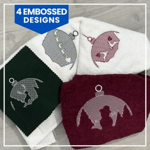 Op de afbeelding: Vier geborduurde handdoeken in wit, donkergroen en bordeauxrood. Elke handdoek heeft een ander reliëfontwerp in een kerstbalvorm. Ontwerpen zijn onder meer een hert, kippen en een sneeuwpop. De tekst "4 EMBOSSED DESIGNS" staat in een blauwe doos.