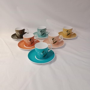 May include: Set of six teacups and saucers with a floral design. The cups and saucers are in various colors, including brown, orange, teal, and yellow.