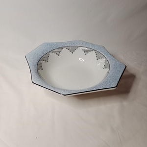 May include: A white ceramic bowl with a blue and black geometric design around the rim. The bowl is octagonal in shape.