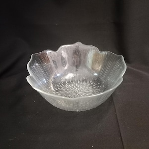 Puede incluir: Cuenco de vidrio transparente con diseño de pétalos florales. El cuenco tiene una superficie texturizada y un patrón de estrella en el centro. El cuenco es de vidrio transparente y es adecuado para servir ensaladas o aperitivos.
