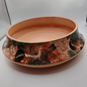 Può includere: Una grande ciotola rotonda in ceramica con un interno color pesca e un design floreale marrone, verde e bianco all'esterno.