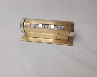 Vintage brass day calendar showing day, month, and the day of the week on a rectangular plinth base 4.5 x 11 x4 cm