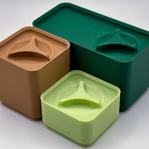 May include: Three square containers with lids. The largest container is green, the medium container is light green, and the smallest container is brown.