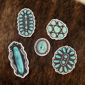 Könnte beinhalten: Fünf Aufkleber mit türkisfarbenen Steinen in verschiedenen Formen und Designs. Die Aufkleber haben einen weißen Rand und sind vor einem braunen und beigen Hintergrund platziert. Die Designs umfassen ovale, runde und längliche Formen mit silberfarbenen Akzenten.