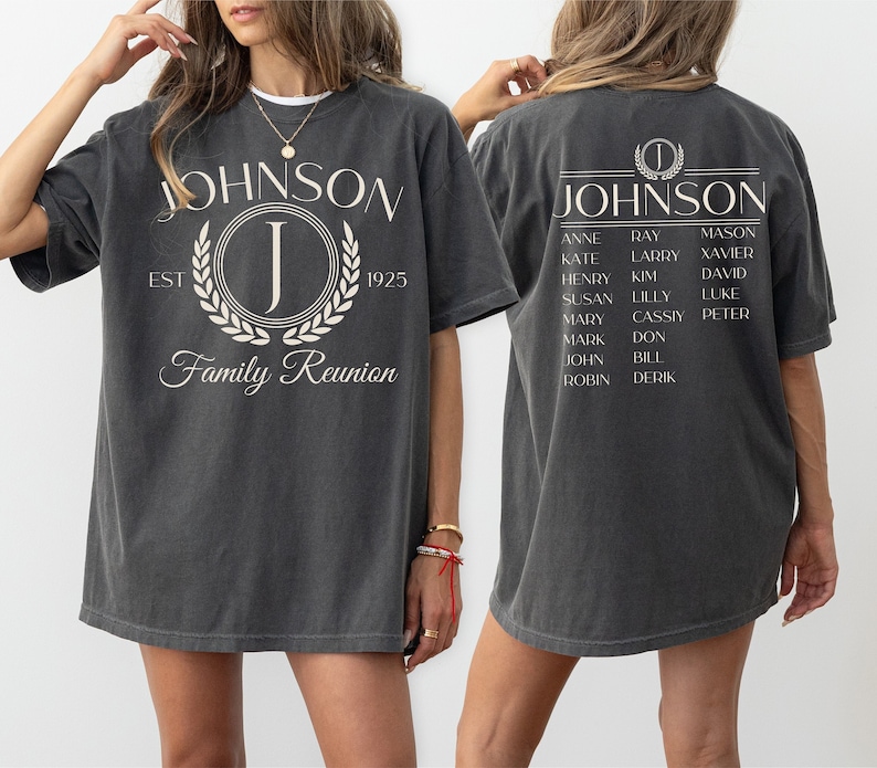 K&ouml;nnte beinhalten: Ein dunkelgraues T-Shirt mit einem wei&szlig;en Grafikdesign, das den Text "JOHNSON" mit einem Kranz und dem Buchstaben "J" darin zeigt. Die R&uuml;ckseite des Shirts hat ein wei&szlig;es Grafikdesign mit dem Text "JOHNSON" und einer Namensliste.