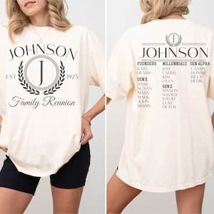 K&ouml;nnte beinhalten: Ein cremefarbenes T-Shirt mit einem schwarzen grafischen Design, das den Text "JOHNSON" mit einem Kranz und dem Buchstaben "J" in der Mitte zeigt. Der Text "EST 1925" und "Family Reunion" sind ebenfalls im Design enthalten. Die R&uuml;ckseite des Shirts zeigt eine Liste von Namen, die nach Generationen geordnet sind, darunter "Gr&uuml;nder", "Millennials" und "Gen Alpha".