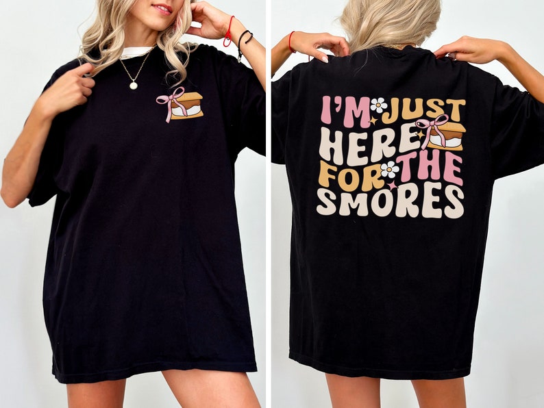 Op de afbeelding: Zwart T-shirt met een afbeelding van een s'more op de voorkant en de tekst "I'm just here for the smores" op de achterkant.