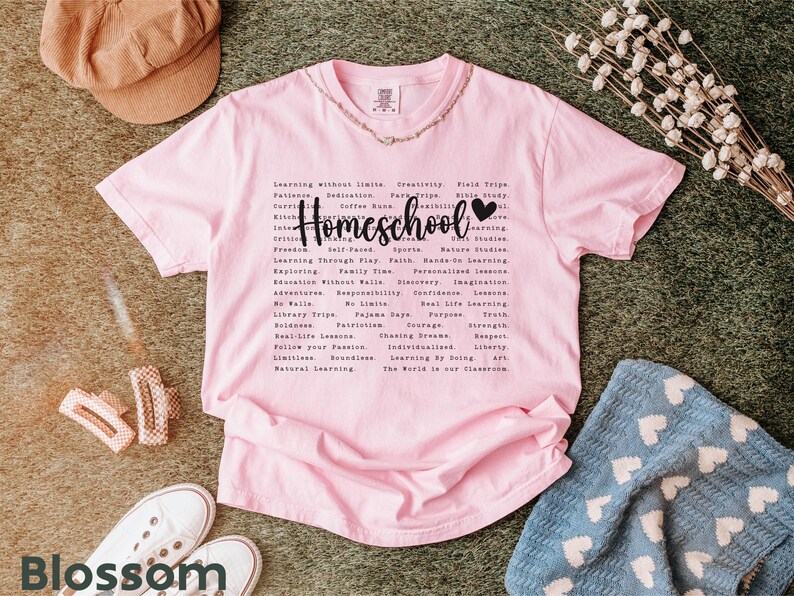 May include: Pink t-shirt with a black graphic that says "Homeschool" with a heart. The graphic lists many reasons why homeschooling is a good choice, such as "learning without limits", "creativity", "field trips", "faith", "personalized learning", "adventure", "real life lessons", "the world is our classroom", and more.