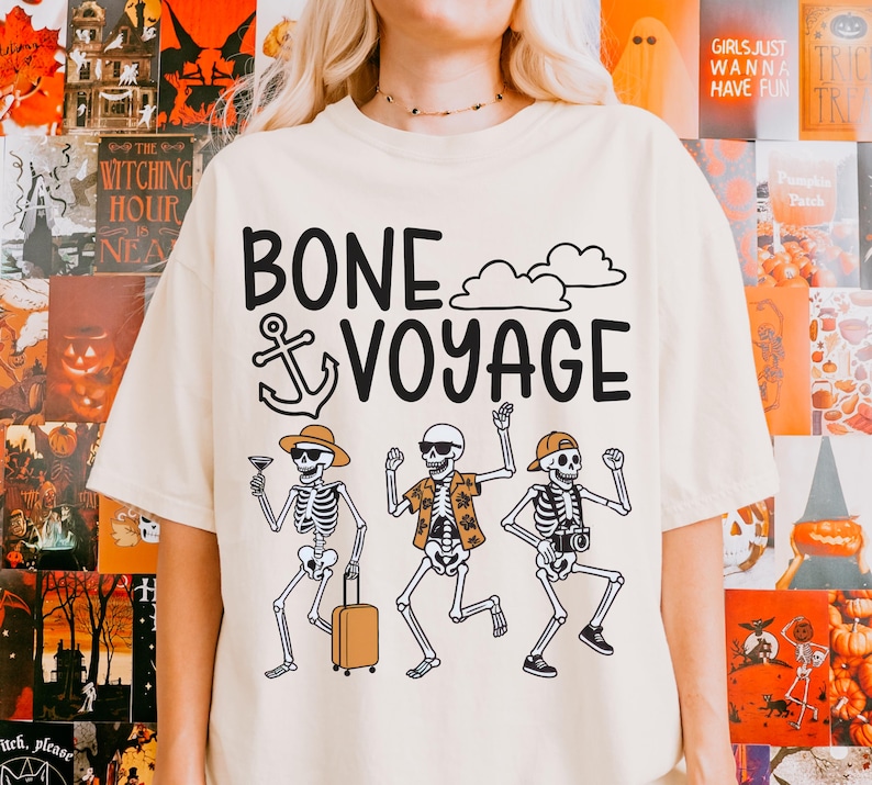 May include: Cream-colored t-shirt with the phrase "BONE VOYAGE" in black, featuring skeleton illustrations. One skeleton holds a cocktail, another a suitcase, and the third a camera. The design includes clouds and an anchor.