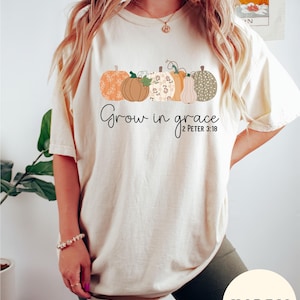 May include: A cream colored t-shirt with a graphic of pumpkins and the text "Grow in grace 2 Peter 3:18".