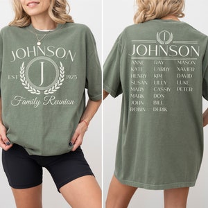 K&ouml;nnte beinhalten: Ein gr&uuml;nes T-Shirt mit dem Text "JOHNSON" und einem gro&szlig;en Buchstaben "J" in einem Kranz. Die R&uuml;ckseite des Shirts tr&auml;gt den Text "JOHNSON" mit einer Liste von Namen darunter.