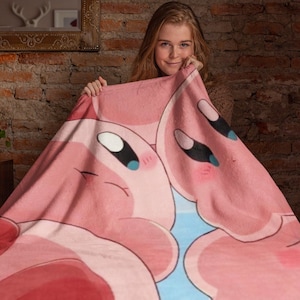 May include: A pink fleece blanket with a cartoon image of two pink characters with large eyes and smiling faces.