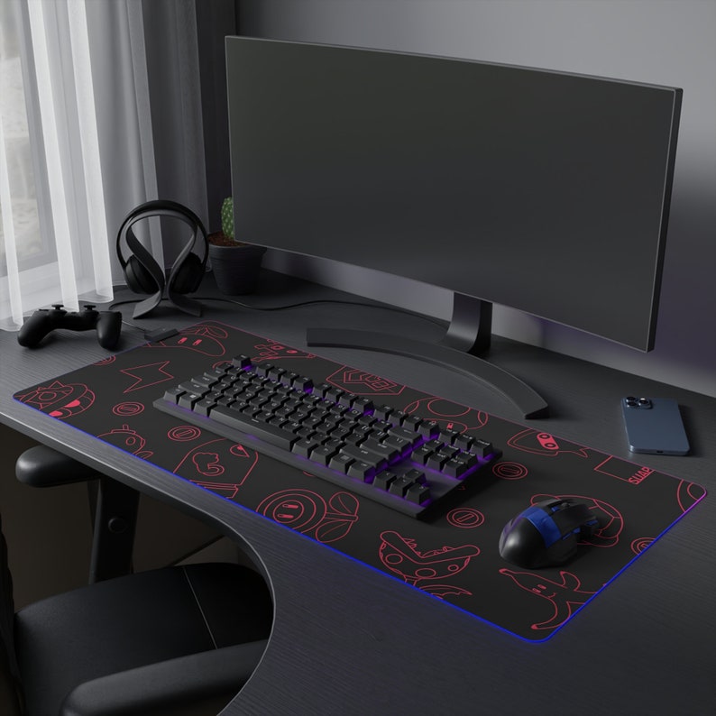 May include: A black gaming keyboard with a red and white design is on a black and red gaming mousepad with a blue LED light. A black computer monitor is in the background.