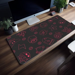 May include: A black gaming mouse pad with a pink outline of various video game characters and symbols. The mouse pad is on a wooden desk.