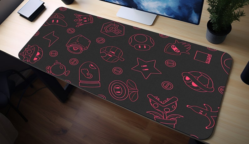 May include: A black gaming mouse pad with a pink outline of various video game characters and objects. The characters include a star, a mushroom, a turtle, a plant, and a bomb. The text "SNAPE" is visible in the upper right corner of the mouse pad.
