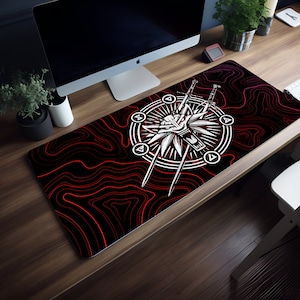 Könnte beinhalten: Eine schwarze und rote Gaming-Mausmatte mit einem weißen Wolfskopf- und Schwerterdesign. Das Design zeigt einen Kreis mit vier Dreiecken darum herum. Die Mausmatte liegt auf einem Holztisch.