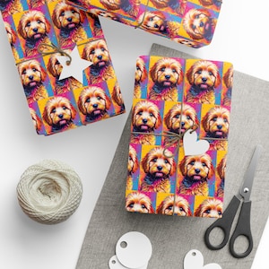 May include: Gift wrap featuring a repeating pattern of a dog's face in a colorful, pop art style. The wrapping paper is tied with twine and adorned with paper tags. A ball of twine and scissors are also present.