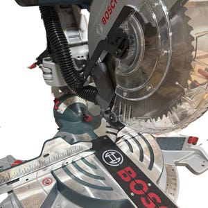 May include: A silver and black Bosch miter saw with a clear blade guard. The saw has a red and black Bosch logo and a measuring scale. The saw is designed for cutting wood and other materials.