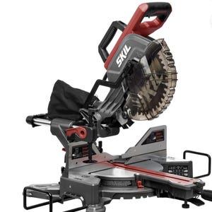 May include: A SKIL brand compound miter saw featuring a gray and red color scheme. The power tool includes a circular saw blade with a transparent safety guard, a black dust collection bag, a metal base, and various adjustment levers and knobs.