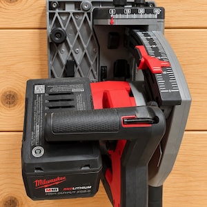 May include: A Milwaukee M18 Redlithium High Output XC8.0 battery attached to a red and gray cordless circular saw. The tool features a gray base plate with a clear angle gauge marked from 0 to 45 degrees and a black textured handle grip.