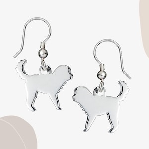 May include: Silver dangle earrings featuring a silhouette of a dog. The earrings have a hook closure.