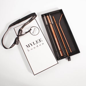 May include: A set of rose gold reusable straws, complete with cleaning brushes, presented in a black box. The packaging features the brand name "MYLEE London". Includes straight and bent straws.