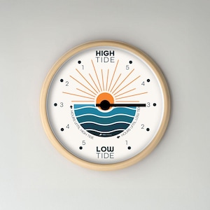 May include: A round wall clock with a light wood frame. The clock face features a stylized ocean scene with a sun and the words "HIGH TIDE" and "LOW TIDE". The clock has black dots for numbers and hands that indicate the time until high or low tide.