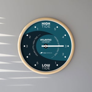 May include: A round, wooden-framed tide clock with a blue face. The clock has a white needle that points to the current tide level. The clock face also has the words "High Tide", "Low Tide", "Atlantic Ocean", and "Hours Until High Tide" and "Hours Until Low Tide".