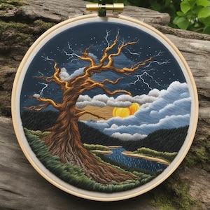 Puede incluir: Arte de bordado en aro que representa un paisaje estilizado con un gran árbol nudoso en primer plano, un río serpenteando por la escena y un sol amarillo poniéndose detrás de las nubes en la distancia.