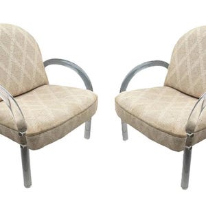 May include: Two armchairs with a light beige diamond pattern fabric. The chairs have clear acrylic armrests and silver legs. The chairs are a modern design and are set against a white background.