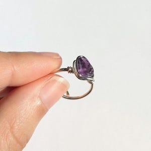 May include: A silver wire wrapped ring with a purple amethyst gemstone.